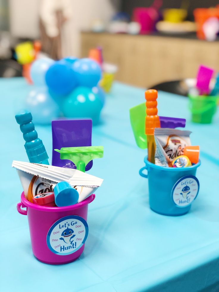 two buckets filled with toothbrushes on top of a blue table