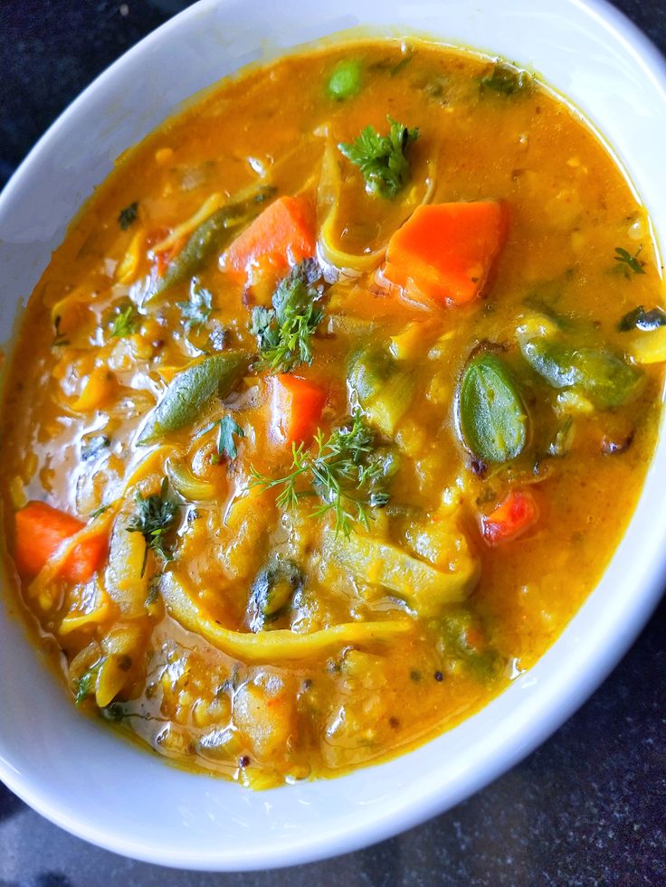 a white bowl filled with vegetable soup on top of a table