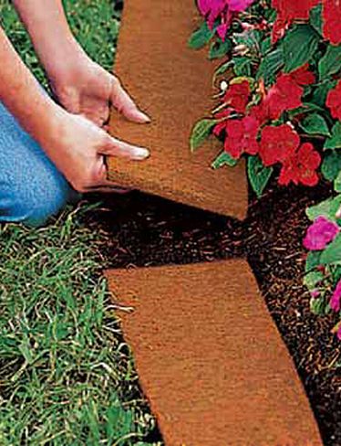 a person kneeling down in the grass with their hand on top of a flower bed