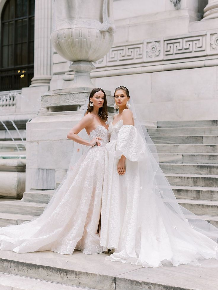 two women in wedding gowns standing on steps