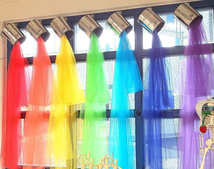 there are many different colored ribbons hanging on the window sill in front of them