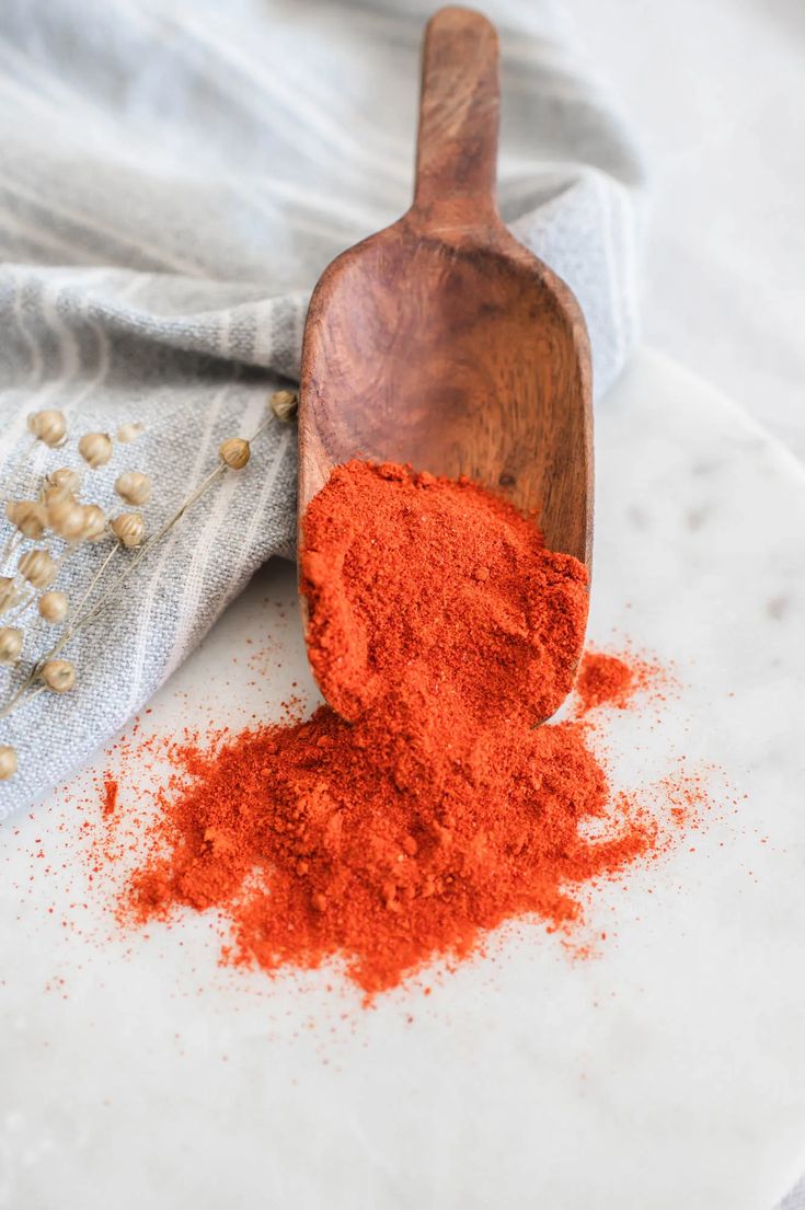 a wooden spoon filled with red powder on top of a table