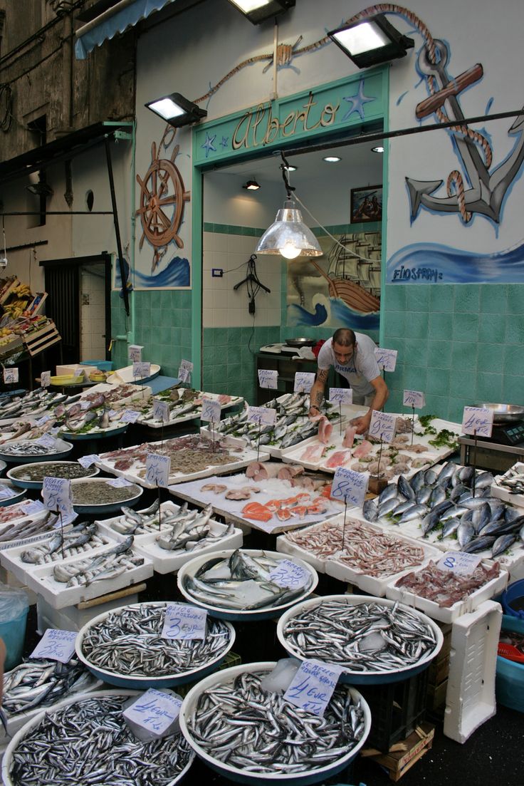 a man standing in front of a fish market filled with lots of different types of seafood