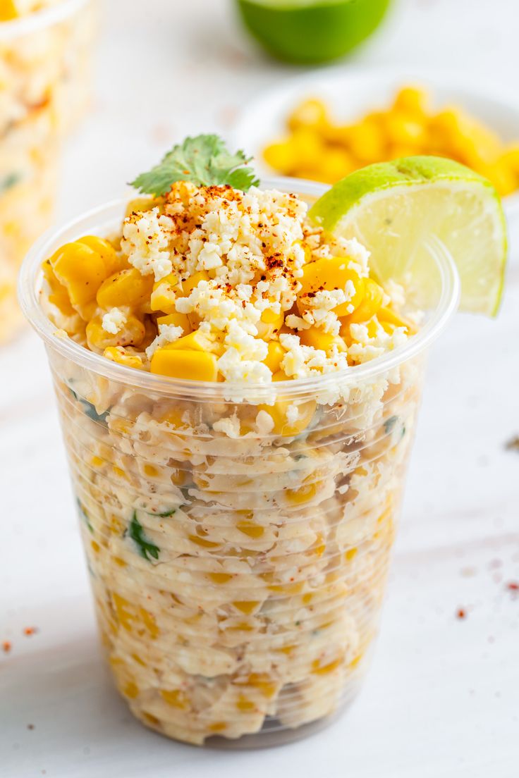 a plastic cup filled with mexican food and garnished with cilantro on the side