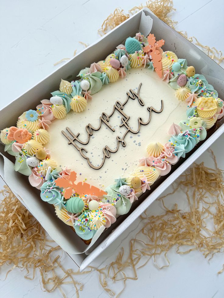 a birthday cake in a box with the word happy written on it, surrounded by seashells