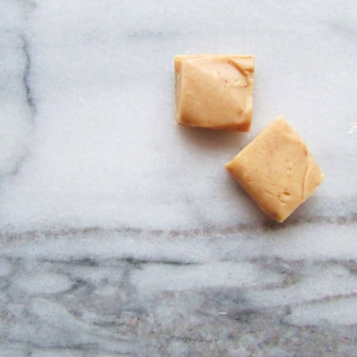 two pieces of cheese sitting on top of a white marble counter next to each other