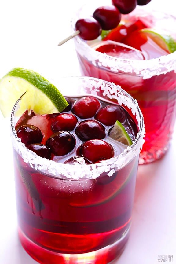 two glasses filled with red liquid and garnished with cherries