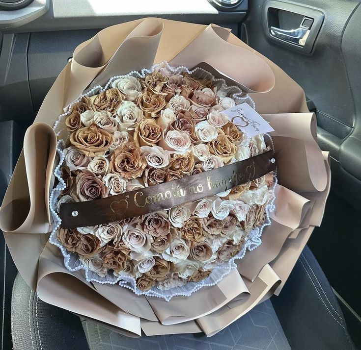 a bouquet of roses in the back seat of a car is wrapped in brown paper