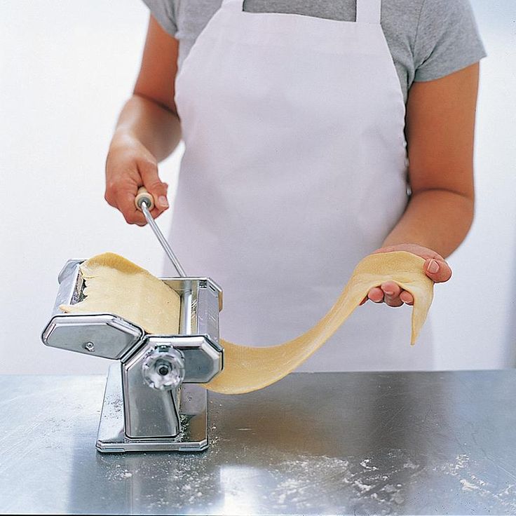 a woman is making pasta with a machine