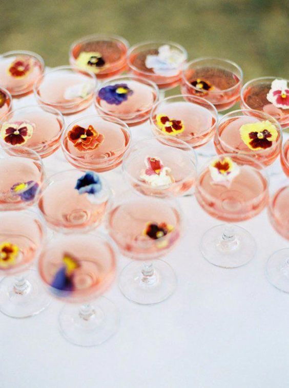 many wine glasses with flowers in them are sitting on a white tablecloth and there is no image here to provide a caption for