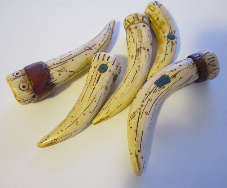 three bananas are sitting next to each other on a white counter top, one has a brown leather band around it's neck and the other is made out of wood