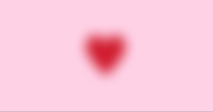 a blurry image of a red heart on a pink background