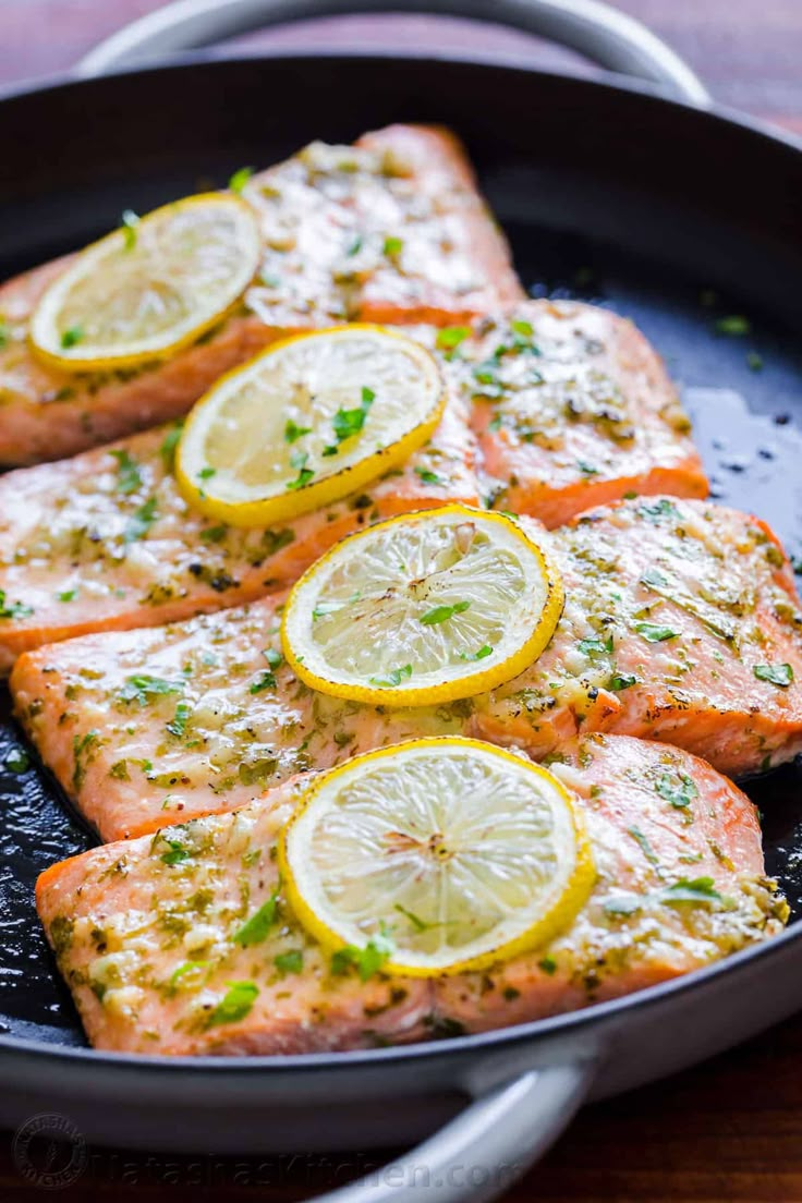 salmon with lemons and herbs cooking in a skillet