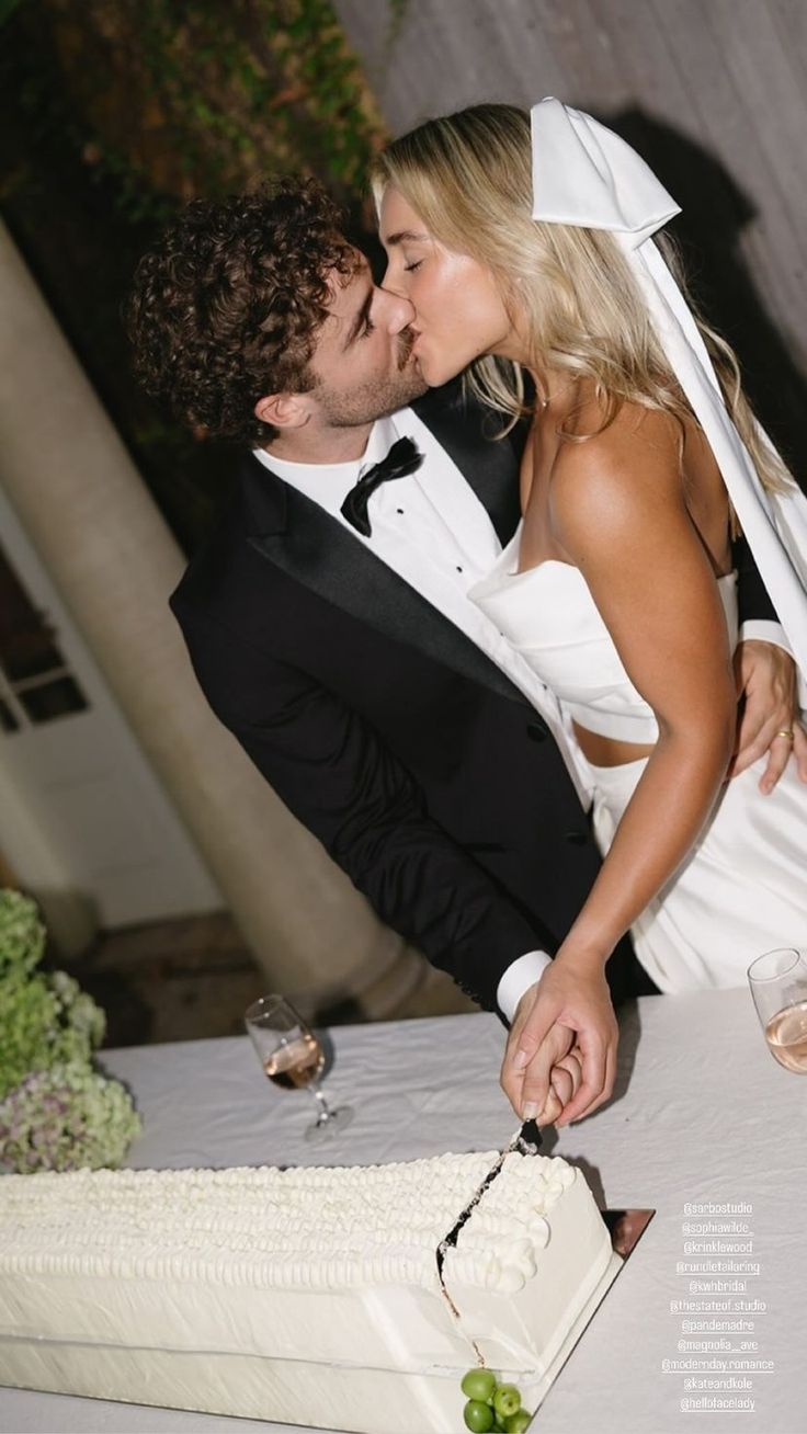 a bride and groom are kissing in front of a wedding cake that has been cut into pieces