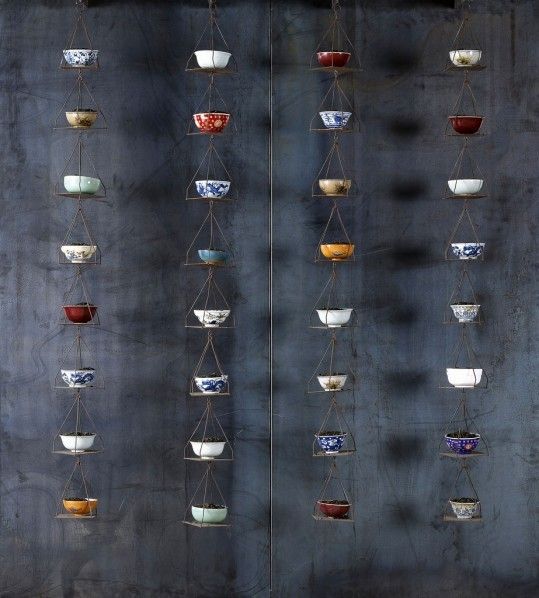 several bowls hanging from strings on a wall