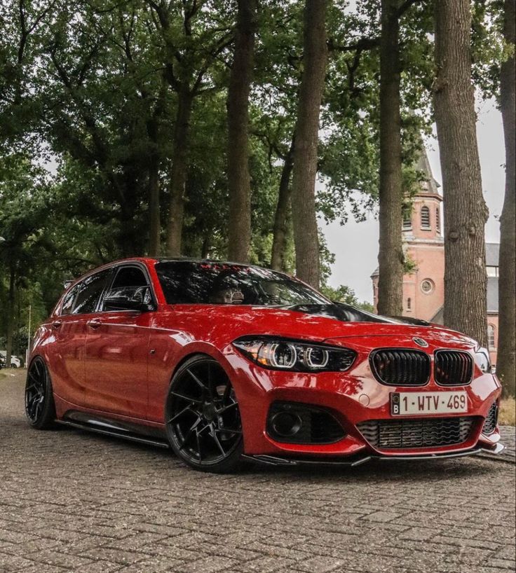 a red car parked in front of some trees