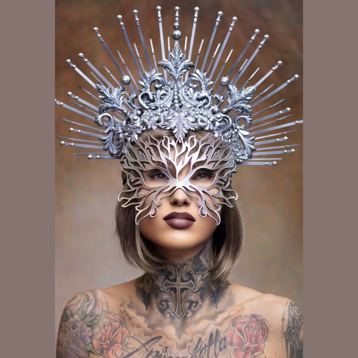 a woman with tattoos wearing a silver mask