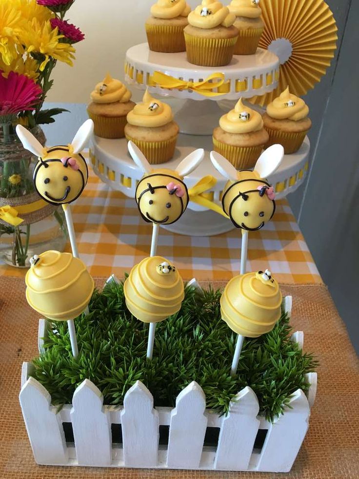 some cupcakes are sitting on sticks in the grass with honeybee toppers