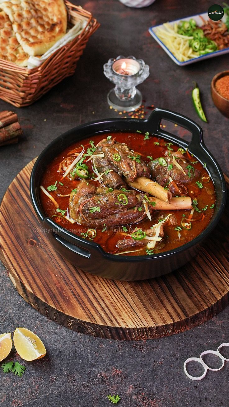 a bowl of stew with meat and vegetables on a wooden board next to bread slices