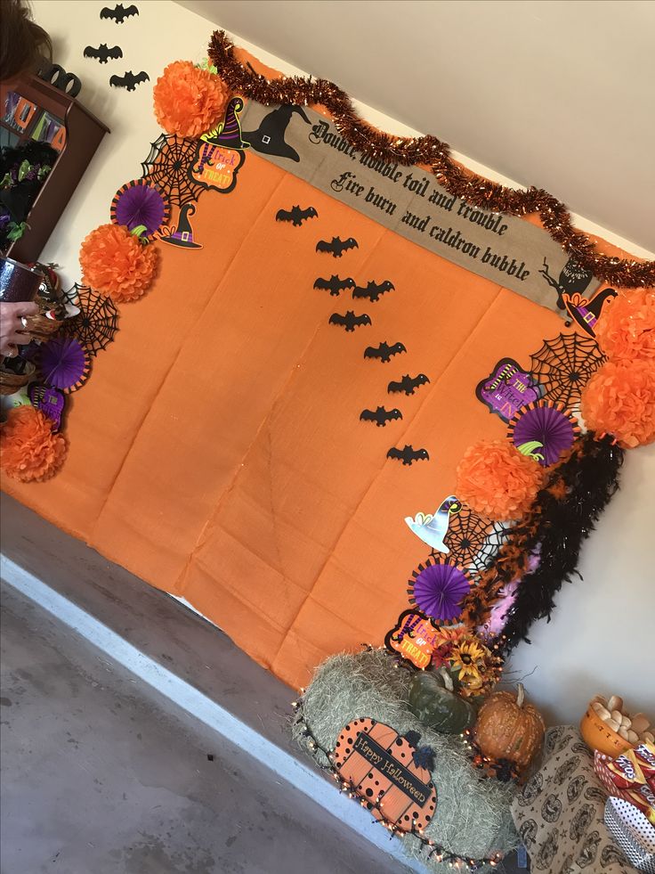 a decorated halloween bulletin board with bats and pom poms on the front wall