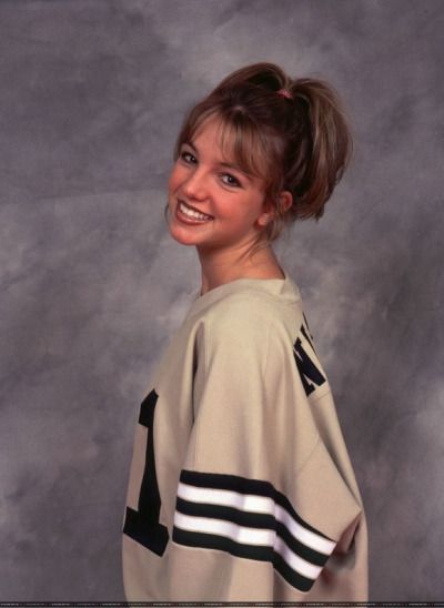 a young woman is smiling and posing for a photo with her hair in a bun