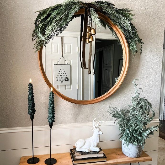 a round mirror hanging on the wall above a wooden table with plants and other decorations