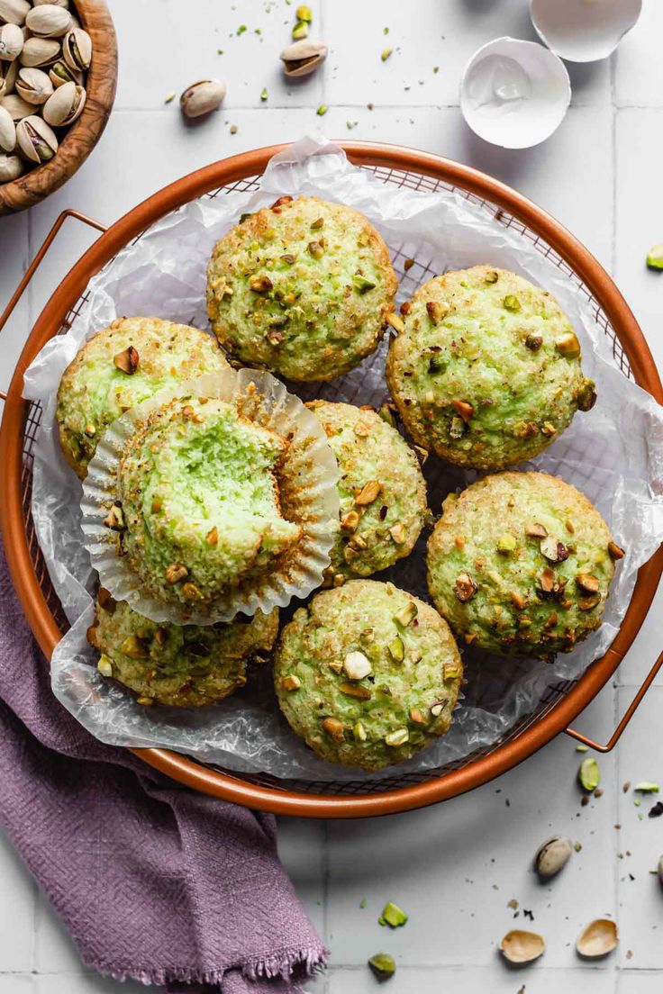 a plate filled with muffins on top of a wooden table next to nuts