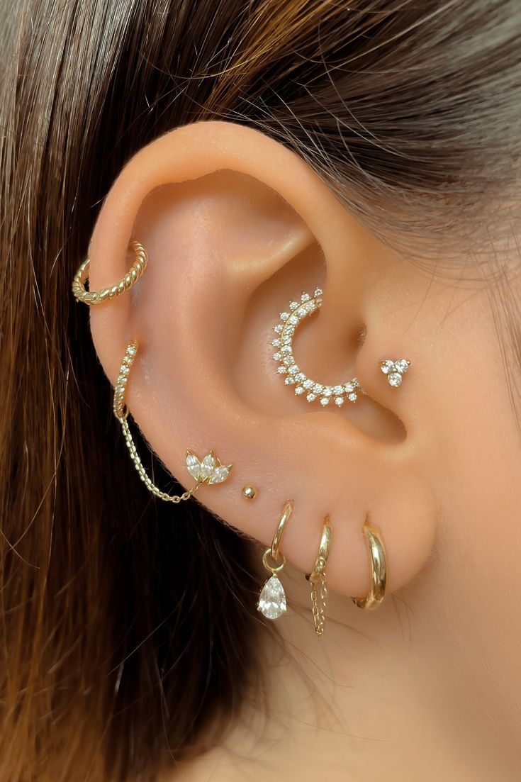 a woman wearing ear piercings with pearls and chains on her ears, in the shape of a crescent