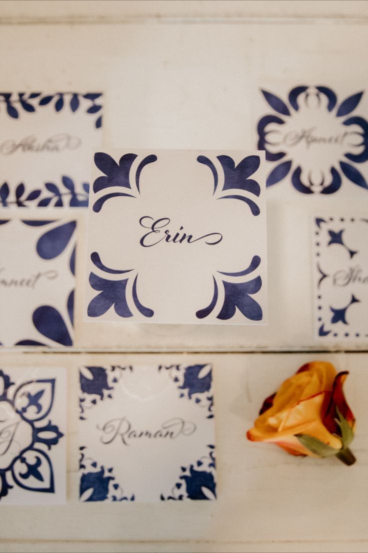 there is a flower on the table next to some place cards that are decorated with blue and white designs