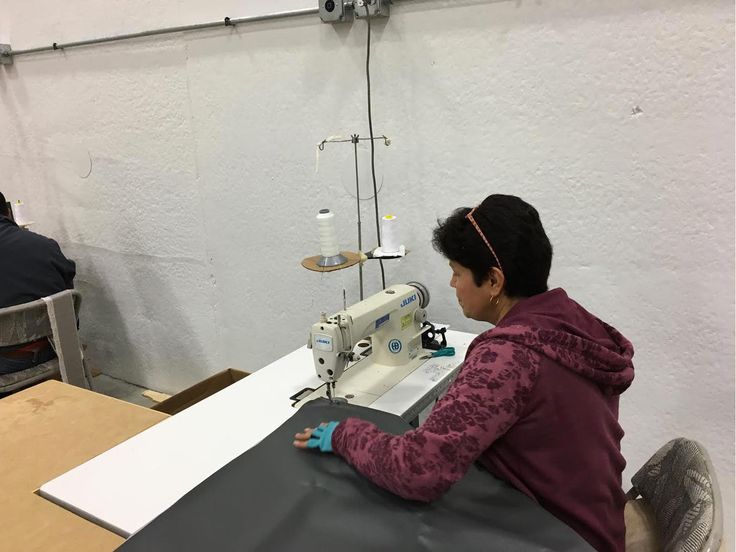 a woman sitting at a table working on a sewing machine