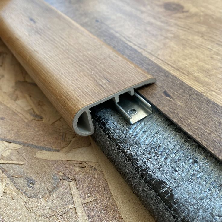 a close up of a wooden floor with a metal handle on the end and wood grain