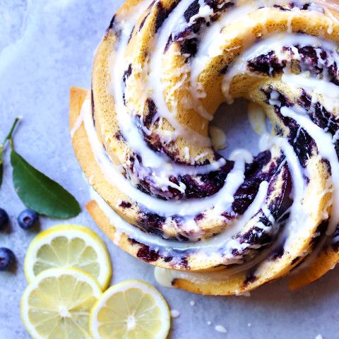 a blueberry roll with icing on top and sliced lemons next to it