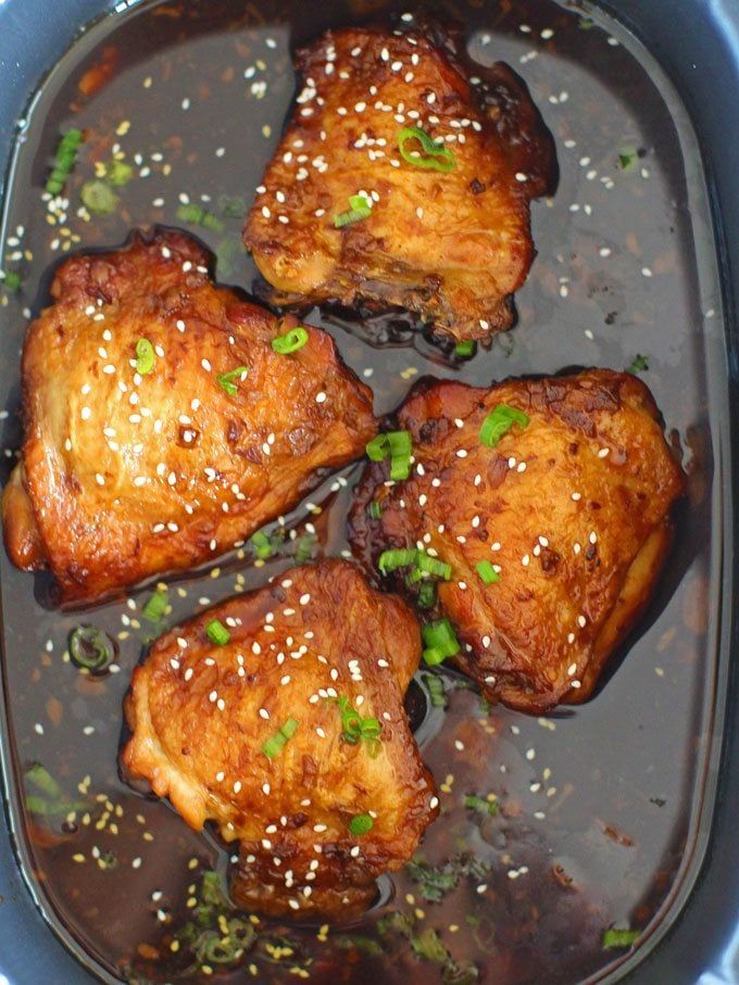 four pieces of chicken with sesame seeds and seasoning in a slow cooker dish