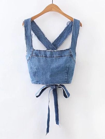 an old pair of jean overalls hanging on a wooden hanger with a white wall in the background