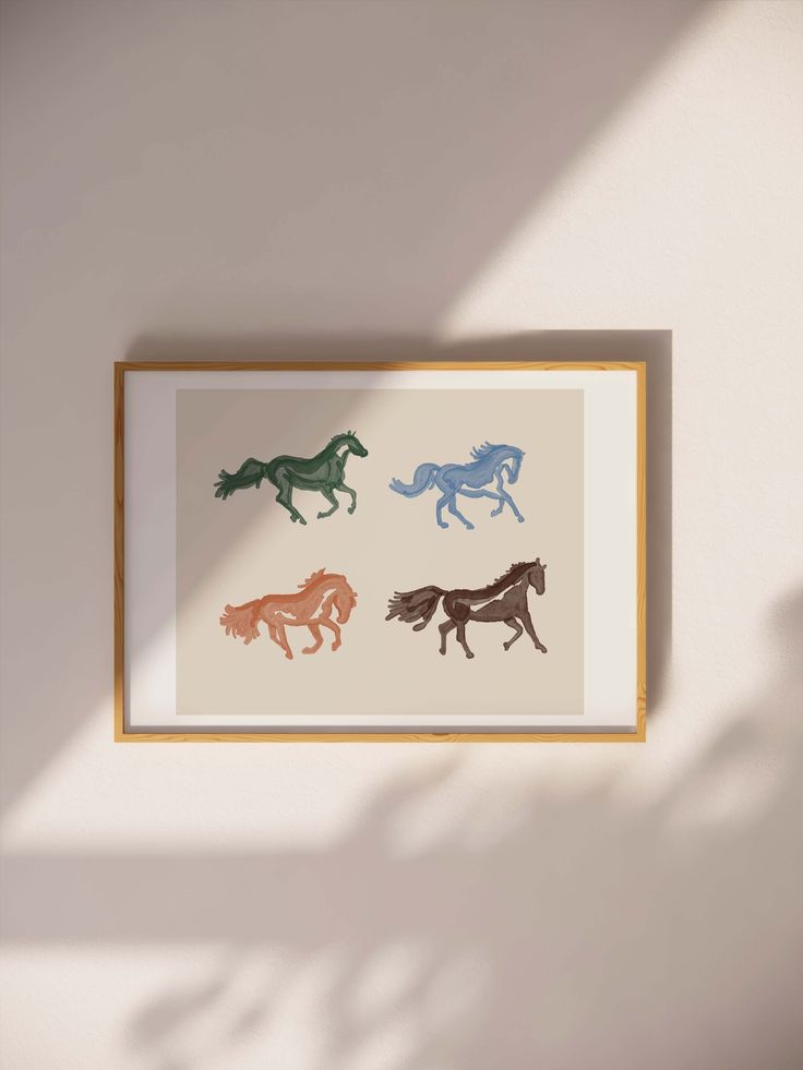 three horses running in different colors on a white wall above a wooden framed art piece