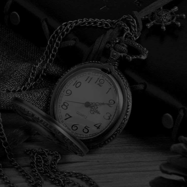 an old pocket watch sitting on top of a table next to a chain link wallet