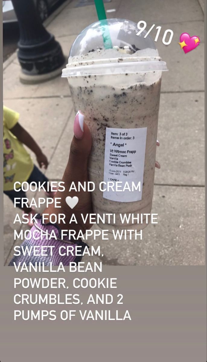 a person holding up a cup of ice cream on the sidewalk with cookies and cream in it