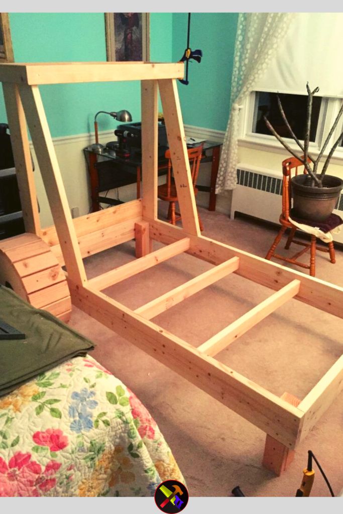 a wooden bed frame sitting on top of a carpeted floor next to a window