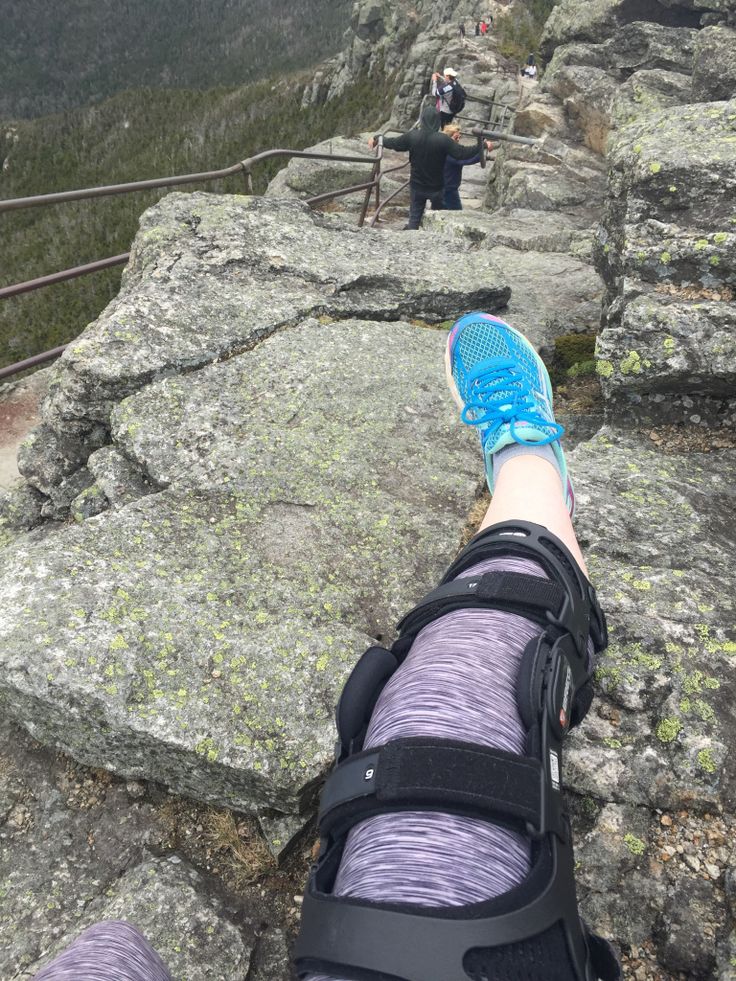 someone's feet on the edge of a cliff with mountains in the background