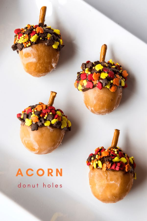 four donuts decorated with candy and sprinkles are on a white plate