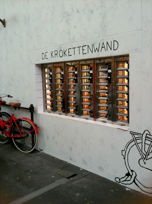 a red bike parked next to a white building with graffiti on it's side