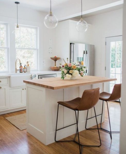 a kitchen island with two stools in front of it and flowers on the counter