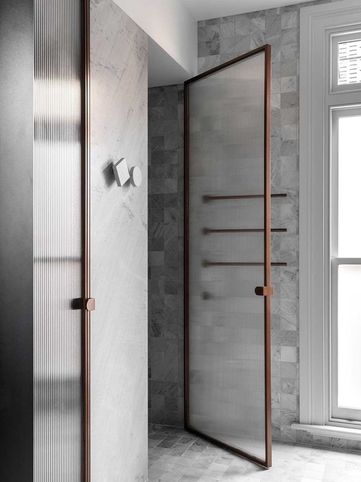 an open shower door in a bathroom with marble walls and floor tiles on the wall