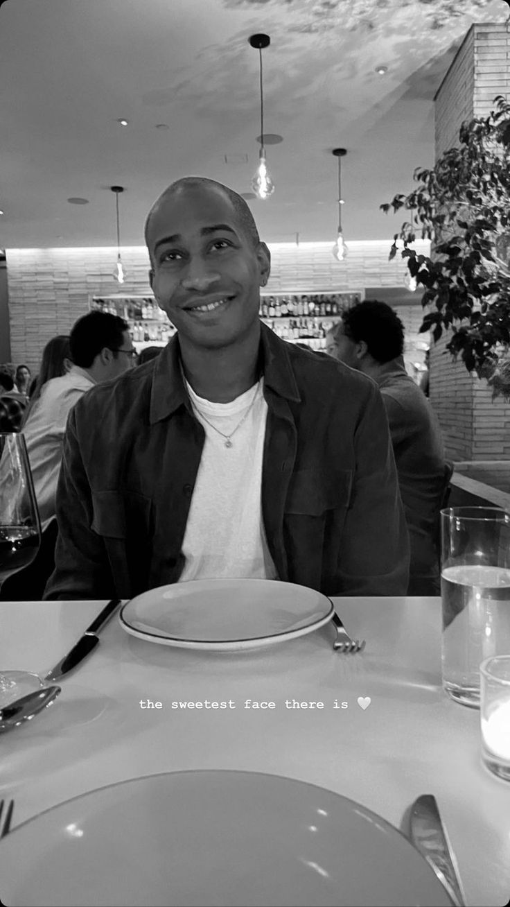 a black and white photo of a man sitting at a table with a plate in front of him