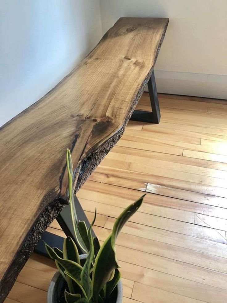 a wooden bench sitting on top of a hard wood floor next to a potted plant