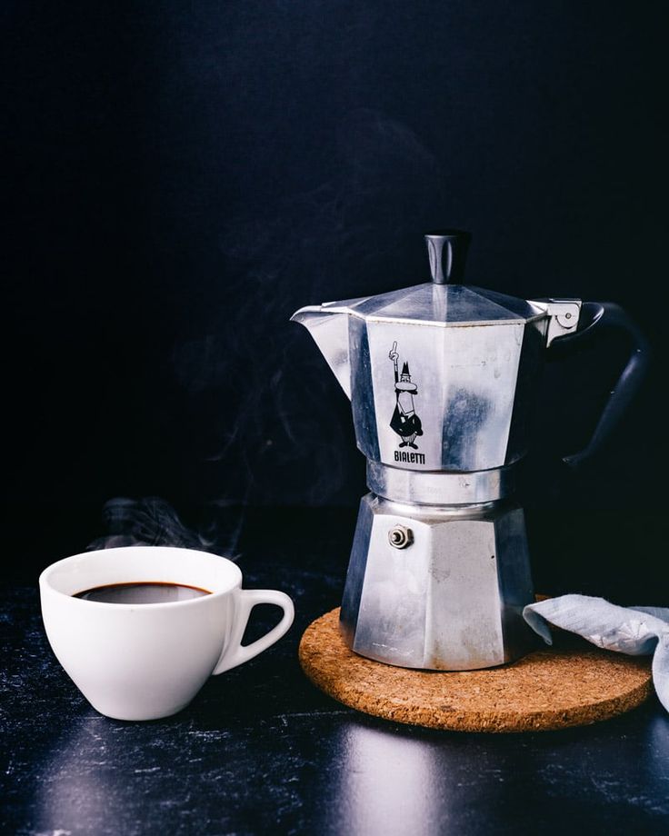 a coffee maker sitting on top of a counter next to a cup and saucer