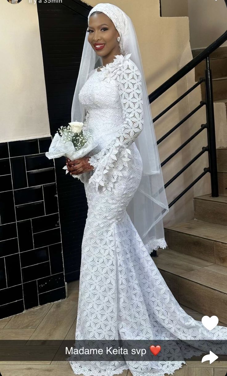 a woman in a wedding dress standing on stairs with her veil draped over her head