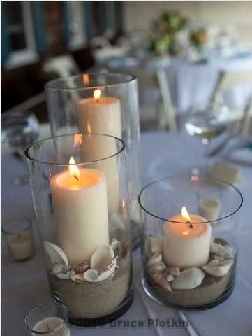 candles are sitting in glass vases with seashells on the bottom and sides