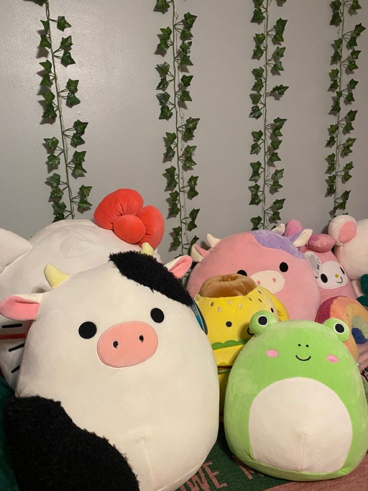 several stuffed animals sitting on top of a bed next to green plants and ivys