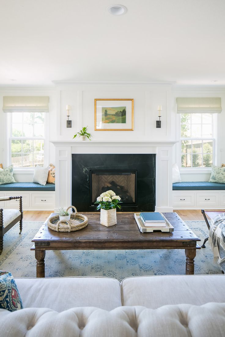 a living room filled with furniture and a fire place in front of a fireplace surrounded by windows